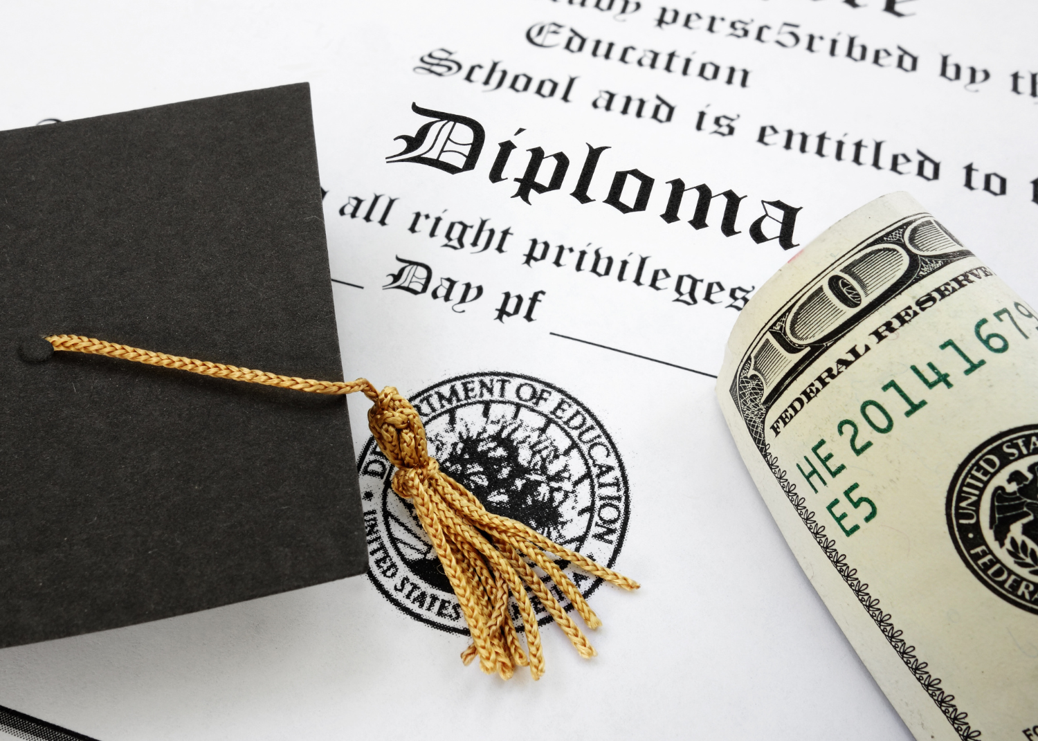 graduation cap and money sitting on top of diploma