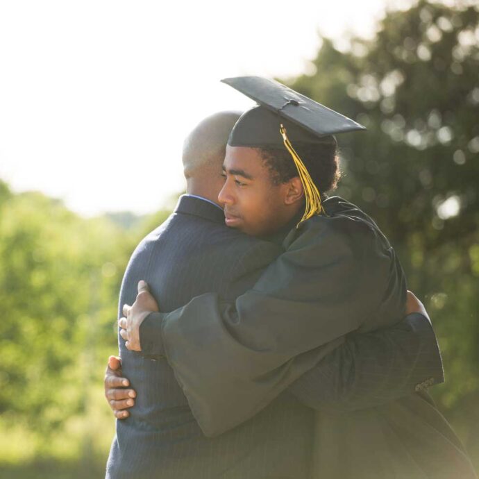 African American graduate hugging family member